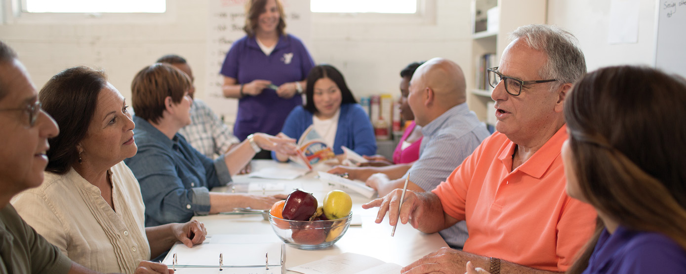 adult learning group gathered around a table taking notes