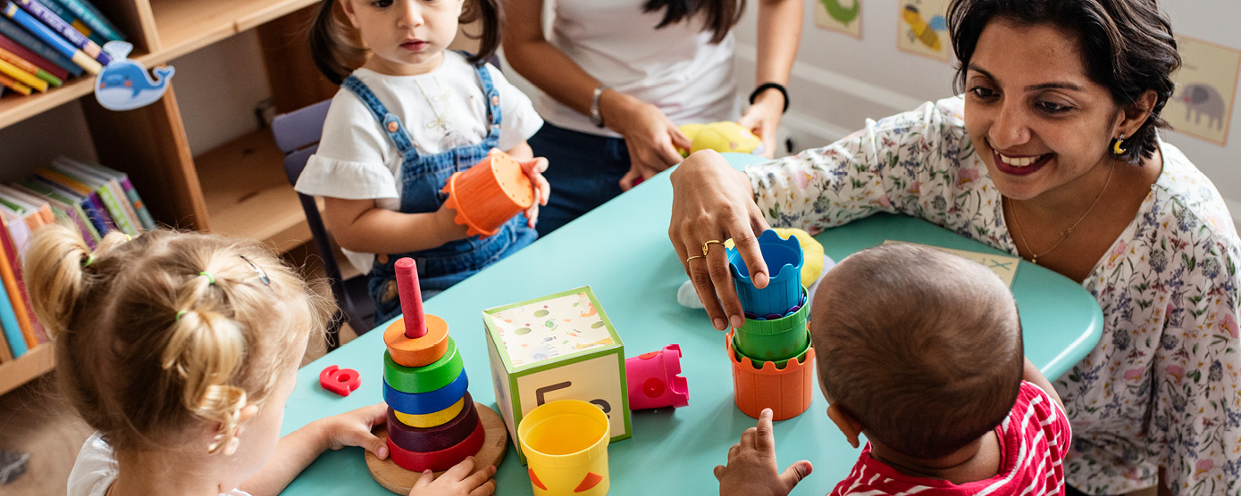 professional adult helping preschoolers learn