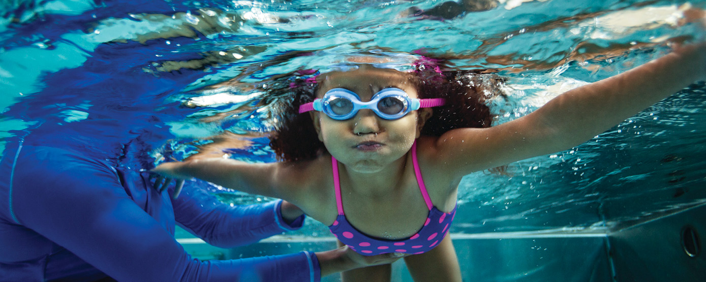 underwater shot of cute kid in goggles learning to swim