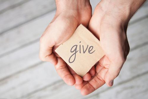 hands holding note that says "give"