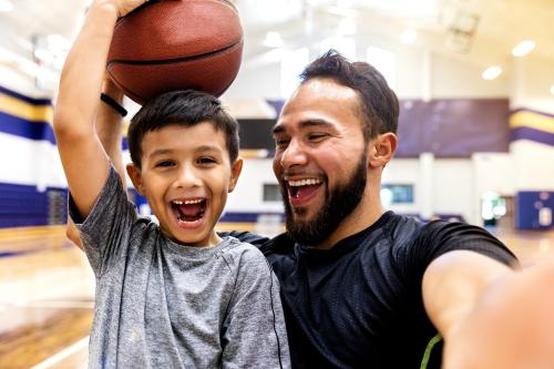 dad and son smiling holding a basketball